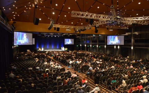 A large conference room with multiple screens and projectors